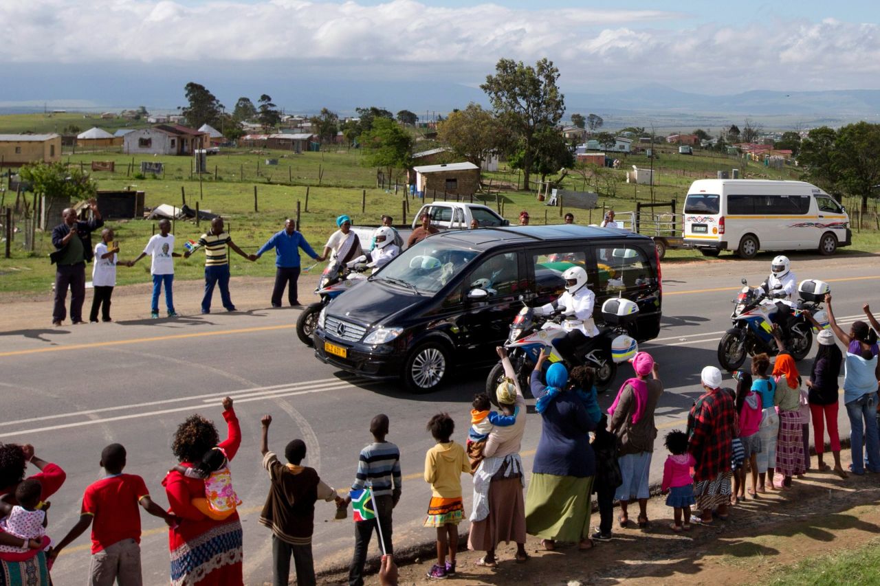 People hold hands as Mandela's hearse proceeds to his hometown and burial site. Mandela became South Africa's first black president in 1994. He had spent 27 years in jail for his activism against apartheid in a racially divided South Africa.