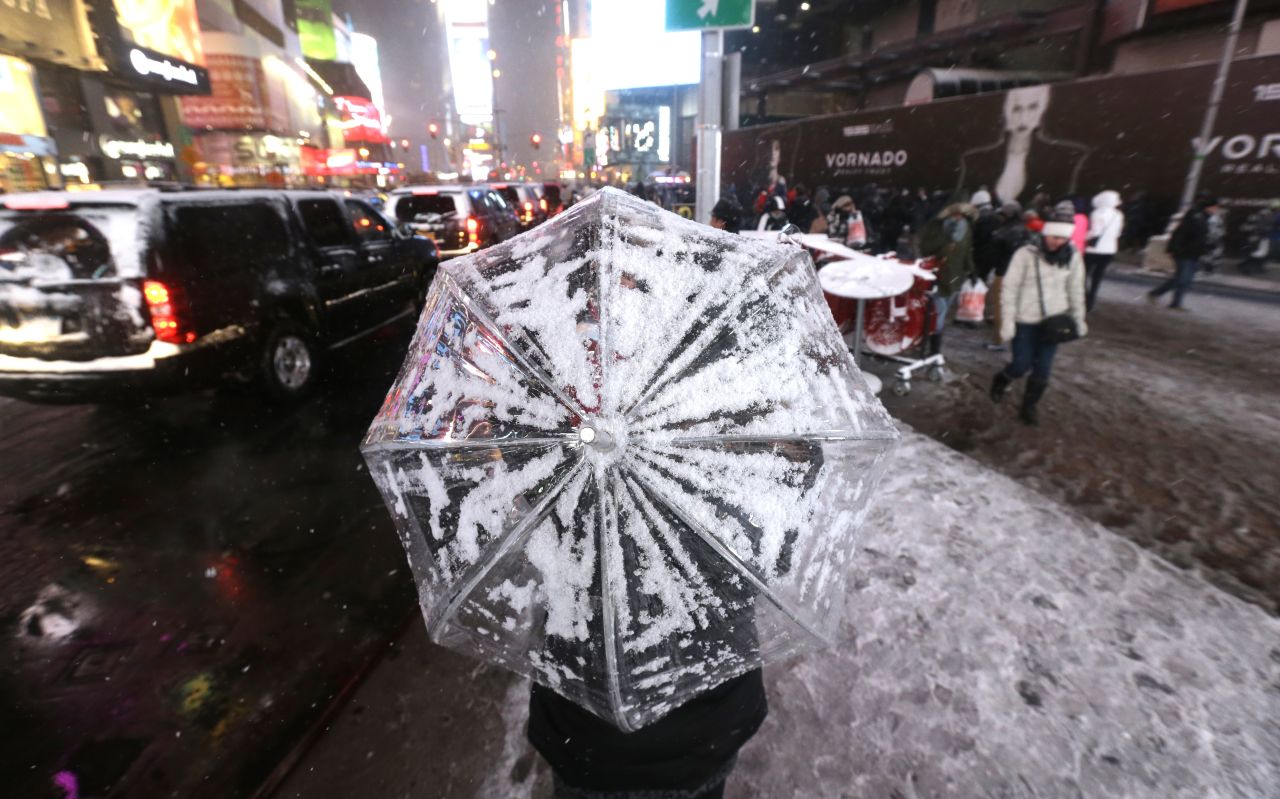 A woman uses an umbrella to protect herself from snow on December 14 in New York's Times Square.