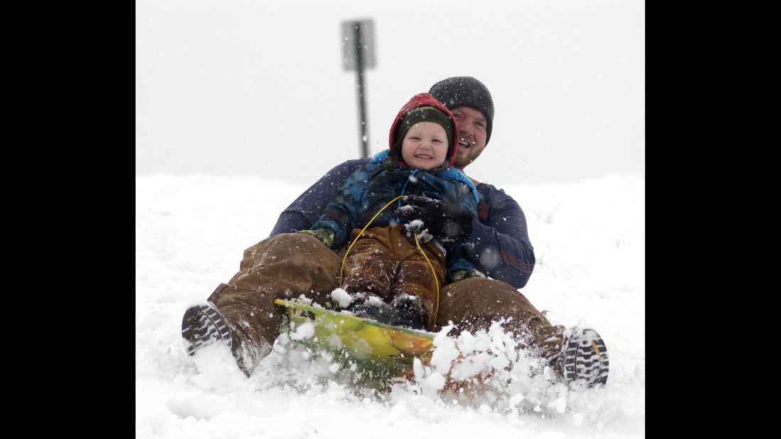 Cooper Reynolds, 3, grins as he sleds down a hill with his father, Ronnie Reynolds, on December 14 at Hudson Family Park in Portland, Indiana.