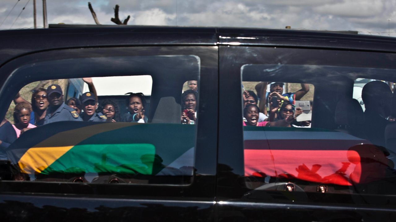 Mourners wave and cheer as the hearse carrying Mandela's body passes through the town of Mthatha on Saturday, December 14.
