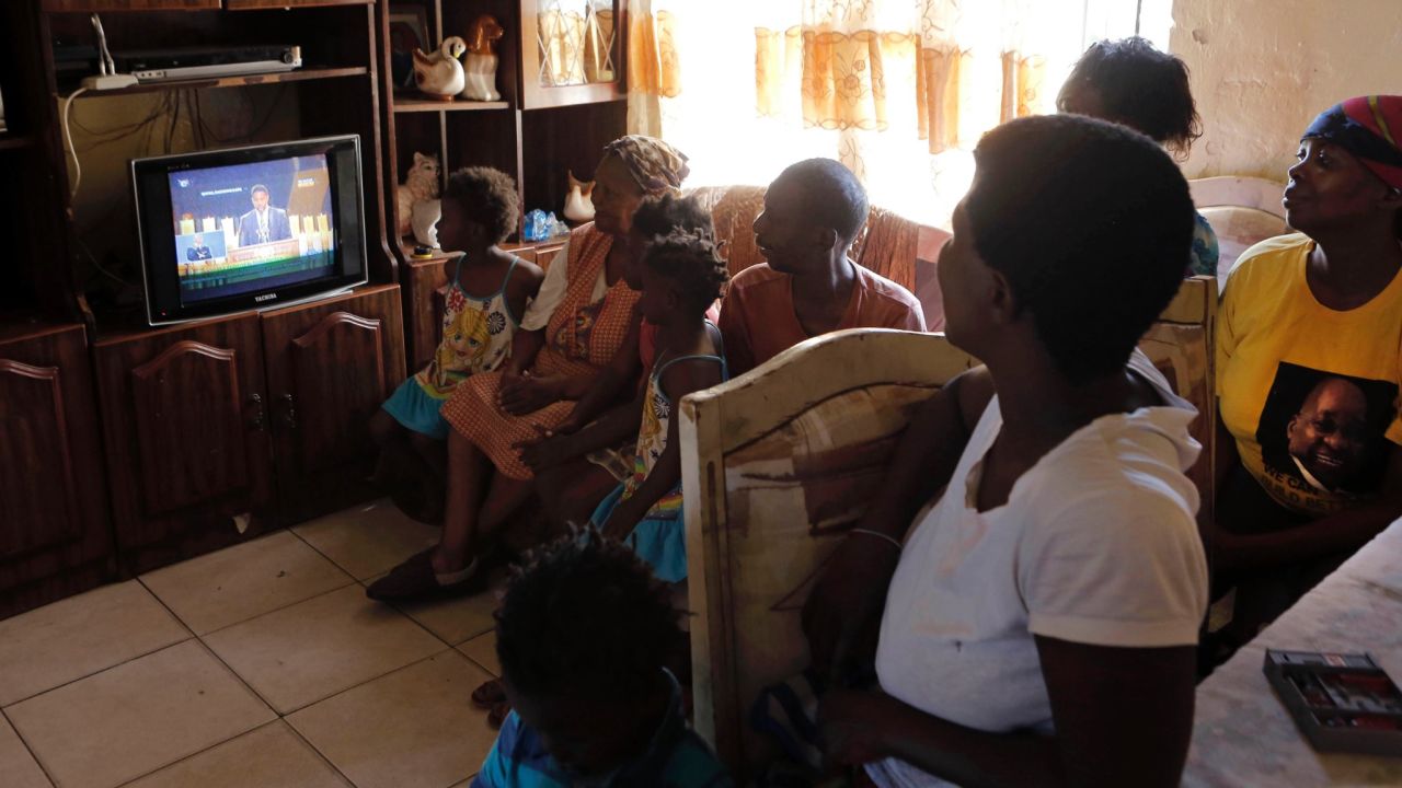A family watches the funeral service from their home in Soweto, South Africa.