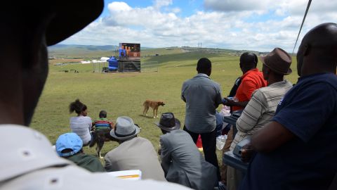 People watch the funeral on a giant screen in Qunu.