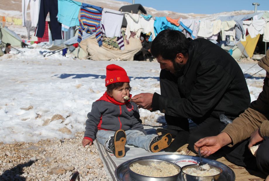 A man feeds his child in the Arsal refugee camp in Lebanon's Bekaa Valley on Sunday, December 15.
