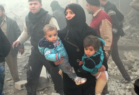 A woman carries children following airstrikes on a rebel area of Aleppo on Sunday, December 15.
