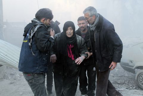 Syrians help a wounded woman following airstrikes in Aleppo on December 15.