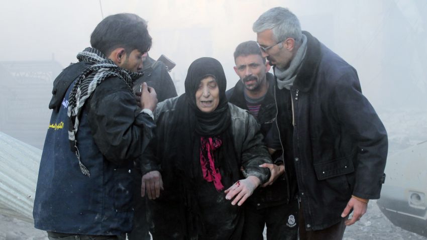 Syrians help a wounded woman following airstrikes on a rebel area in Aleppo on December 15.