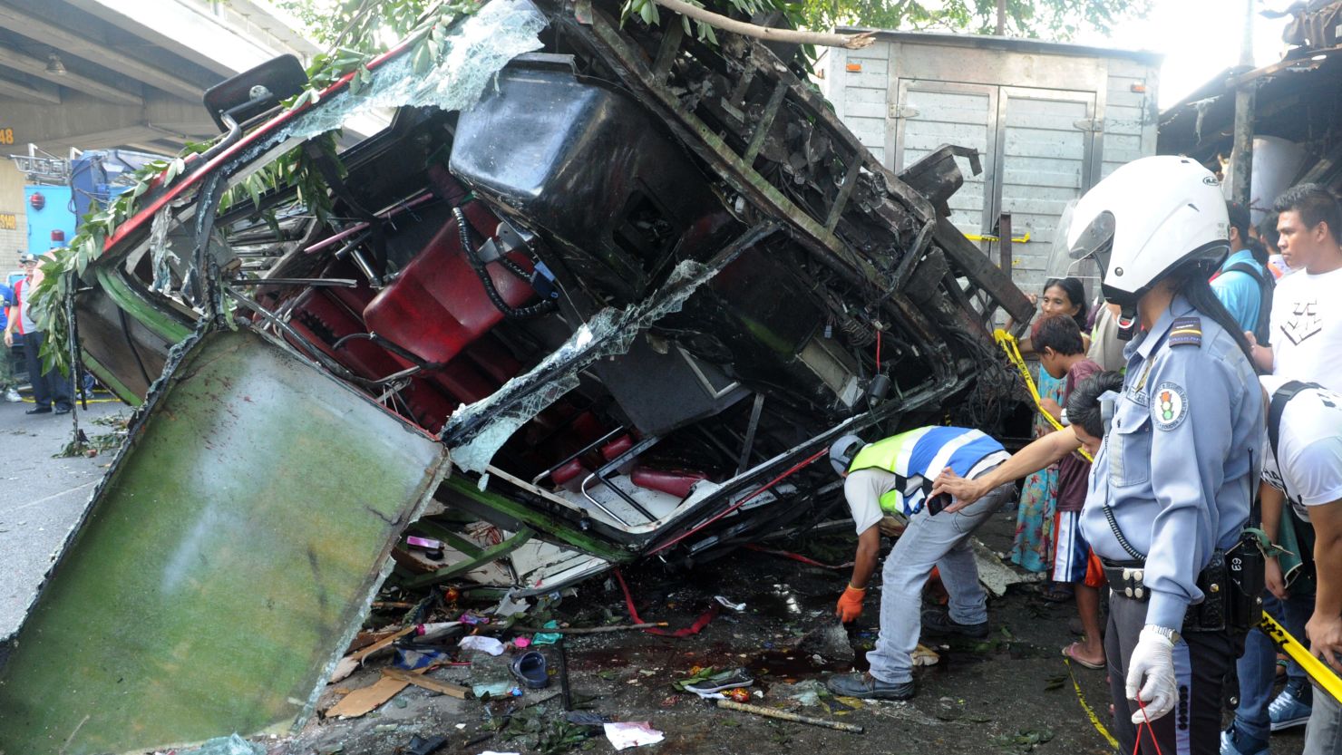 A highway patrol officer collects passengers' belongings from the bus that fell from an elevated highway in Manila.