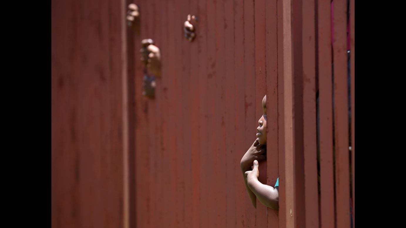 <strong>December 13:</strong> A young boy looks through a fence as he waits in line with thousands of people hoping to board a bus that will take them to view Mandela's body in Pretoria, South Africa.