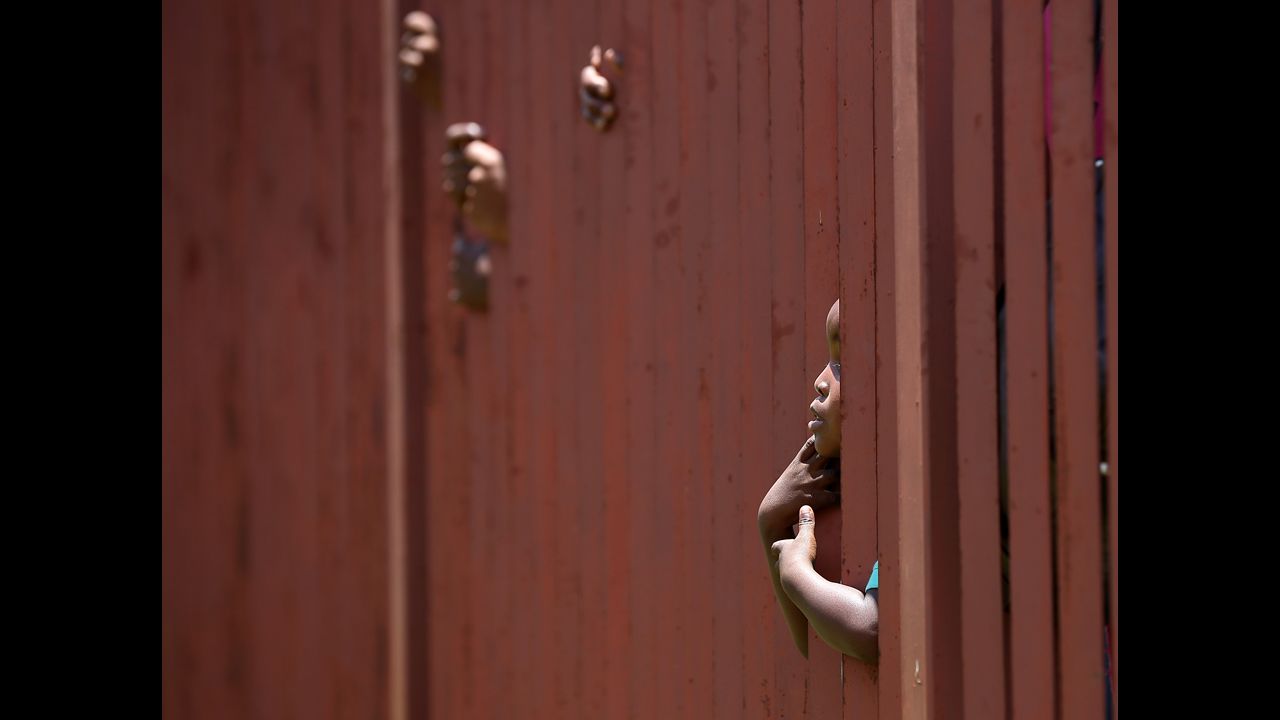 <strong>December 13:</strong> A young boy looks through a fence as he waits in line with thousands of people hoping to board a bus that will take them to view Mandela's body in Pretoria, South Africa.