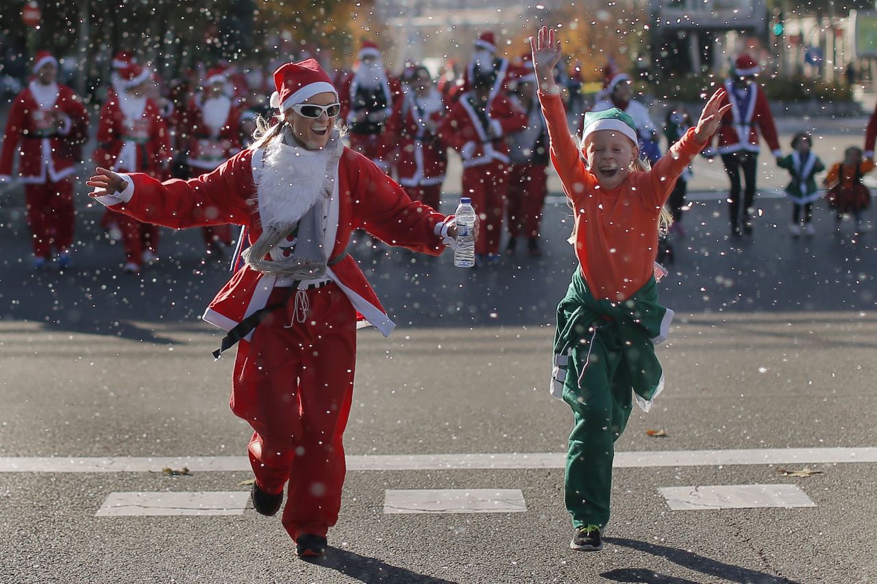 Revelers dressed as Santa Claus run under fake snow during a mini-marathon in Madrid on December 14.