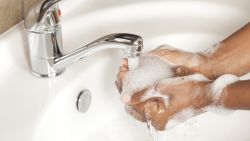 Close up black woman's hands washing with liquid soap in bathroom.