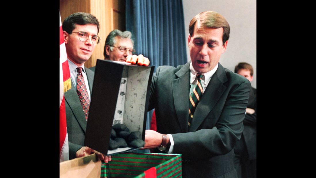 Boehner dumps out coal, which he called a Christmas gift to President Clinton, during a news conference about the federal budget on December 21, 1995. Many government services and agencies were closed at the end of 1995 and beginning of 1996 as a Republican-led Congress battled Clinton over spending levels.