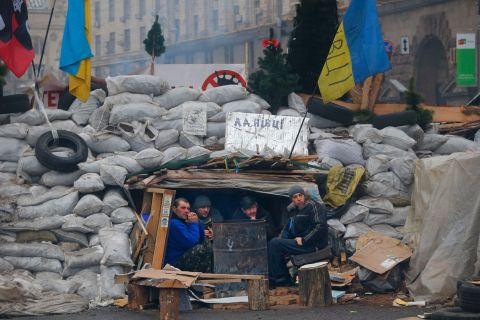 Activists warm themselves beside a bonfire as they guard barricades at Independence Square on Monday, December 16.