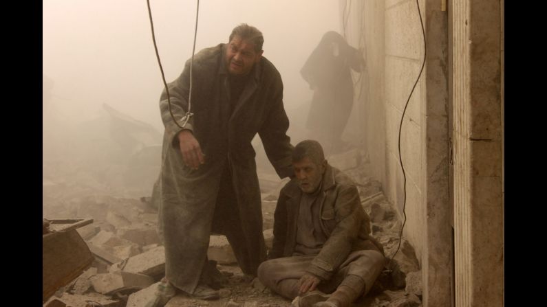 A man sits on the ground after the airstrike in Aleppo on December 17.
