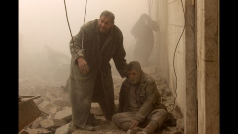 A man sits on the ground after the airstrike in Aleppo on December 17.