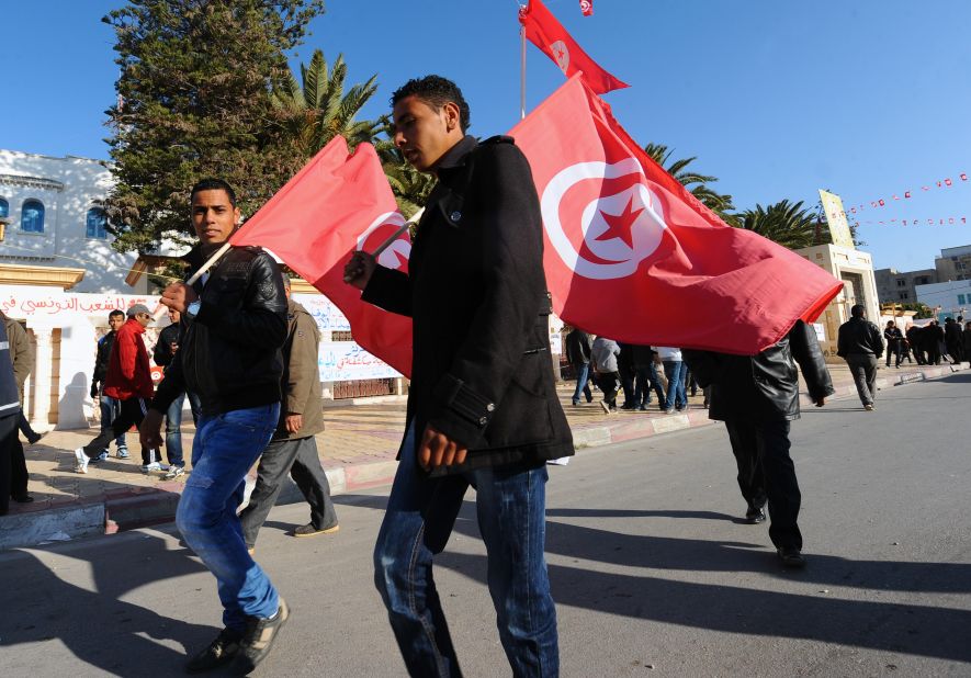 Men wave the national flag to mark the anniversary of the uprising.