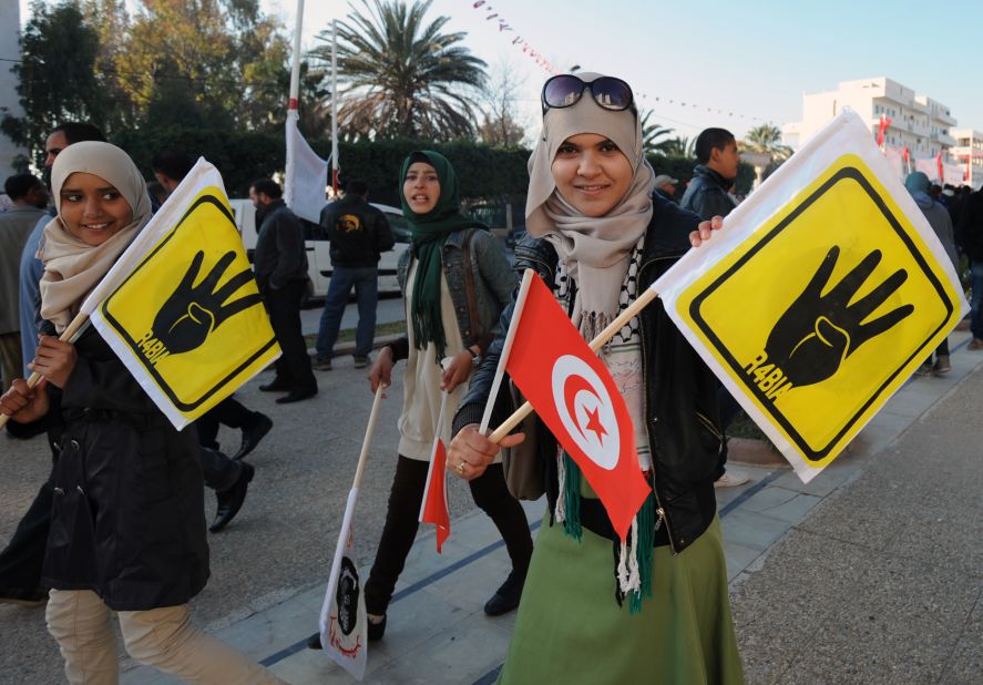Tunisian girls carry flags showing the symbol known as "Rabaa," which means four in Arabic, remembering those killed in the crackdown on the <a href="http://cnn.com/2013/08/14/world/meast/egypt-protests/">Rabaa al-Adawiya protest camp</a> in Cairo, Egypt, earlier in the year.