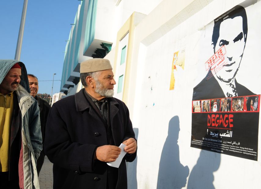 Tunisians look at a movie poster bearing the portrait of deposed President Zine el Abidine Ben Ali.