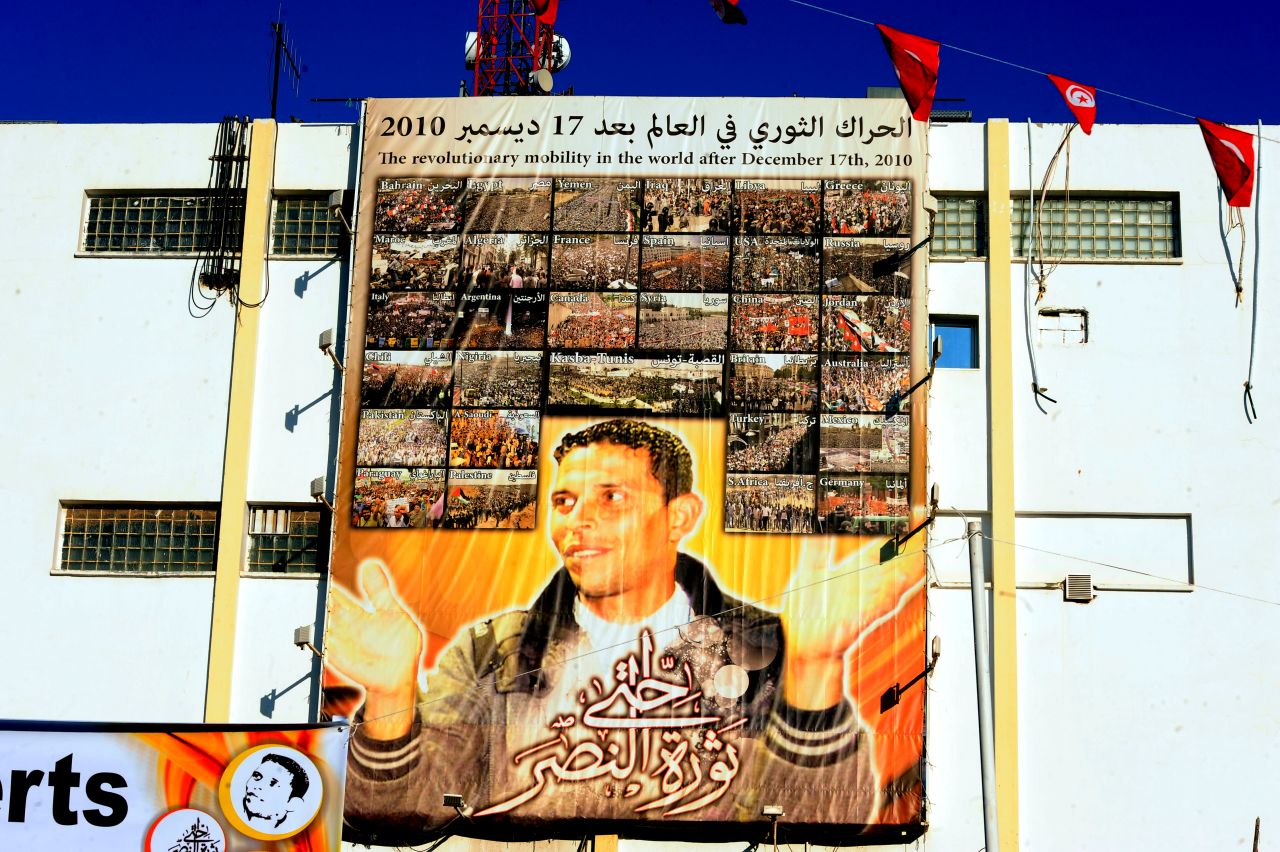 A giant portrait of Mohamed Bouazizi hangs on the wall in the central town of Sidi Bouzid.<a href="http://cnn.com/2011/WORLD/africa/01/16/tunisia.fruit.seller.bouazizi/"> The 26-year old fruit seller who struggled with poverty </a>set himself on fire in front of a government building on December 17, 2010 sparking riots across the country. Al Bouazizi died of his injuries on January 4, 2011.