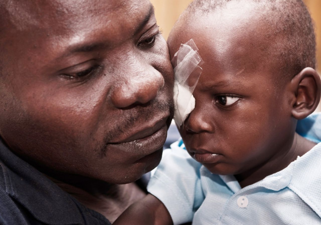 Blessjah Adegoke is embraced by his father after his eye operation.