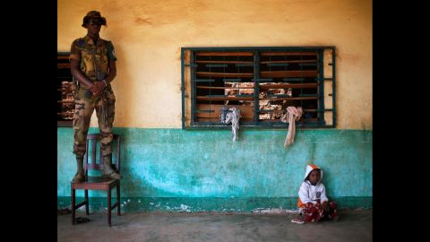 An African Union peacekeeper stands on a chair December 18 as a small child sits on the floor of an Islamic center where refugees have sought protection in Bangui.