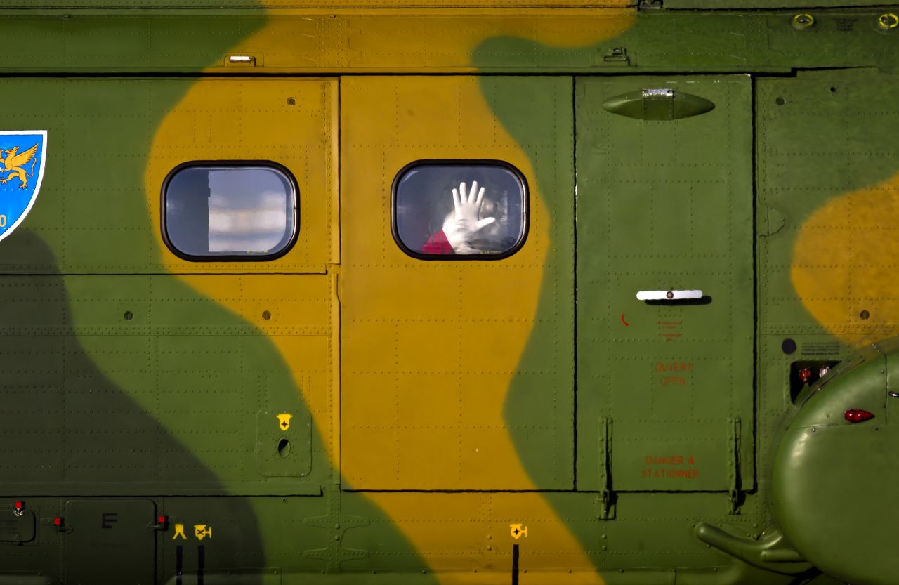 A man wearing a Santa Claus outfit waves from a military helicopter at a Romanian Air Force base in Otopeni, Romania, on December 17. Santa arrived on a helicopter and distributed gifts to children.