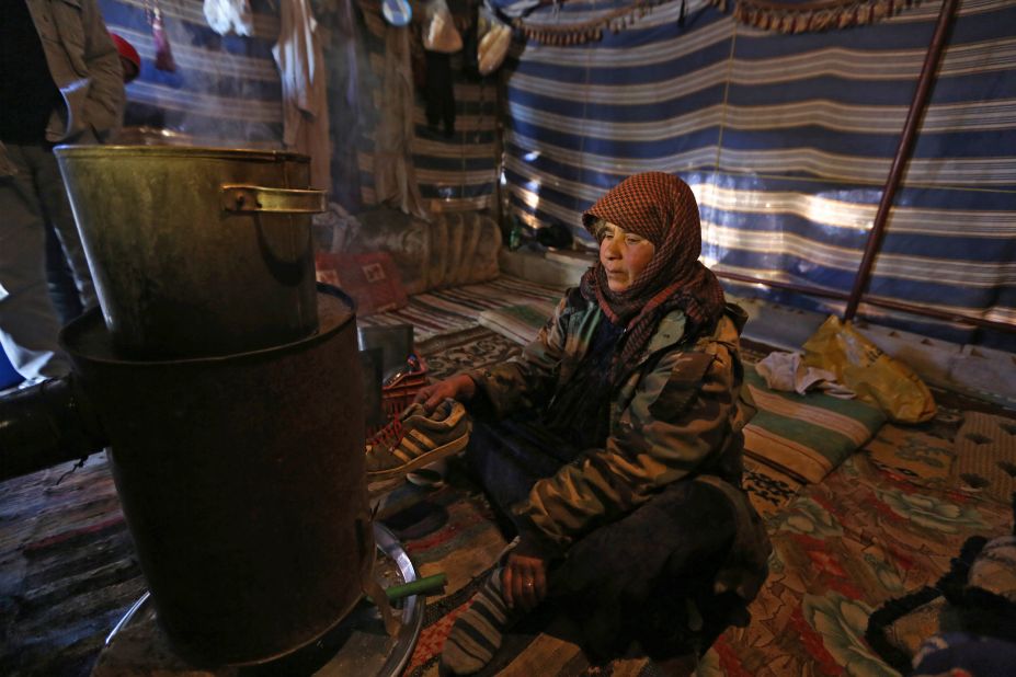 Syrian refugee Mariam al-Hamed burns an old shoe for warmth inside her tent at a refugee camp near Baalbek, Lebanon.