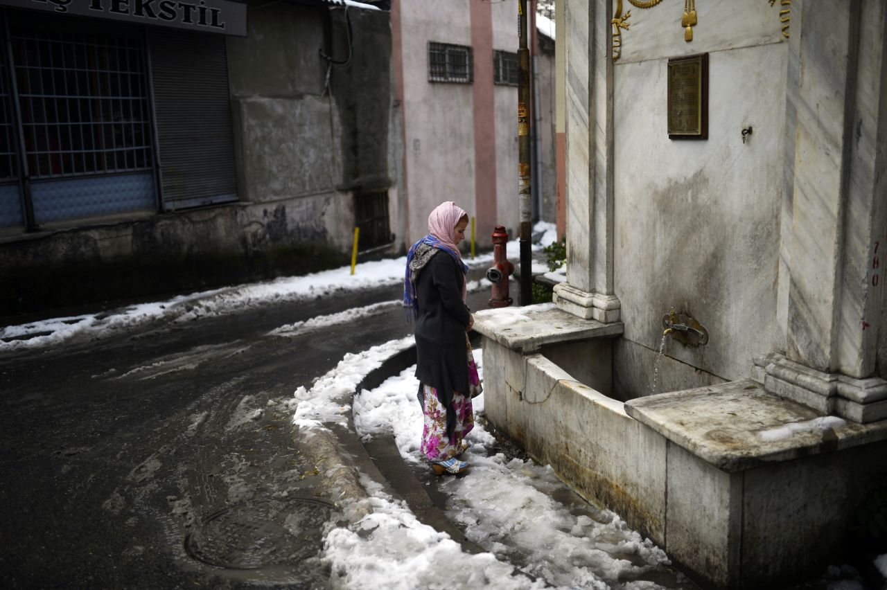 A Syrian woman stands in front of a fountain in Istanbul, Turkey. The recent snowfall brought more misery to refugees in Turkey, who are facing an increasing shortage of supplies.