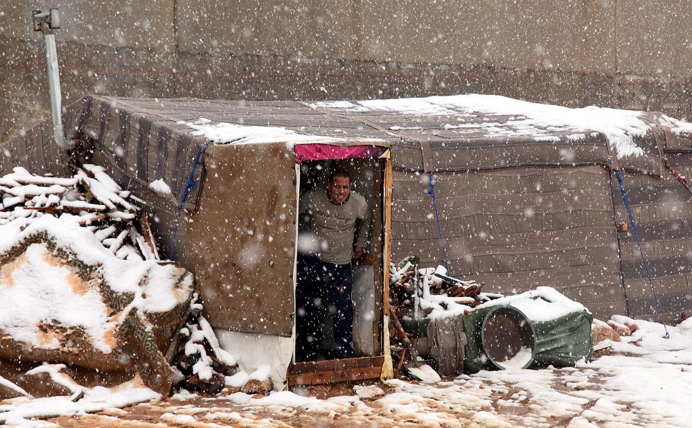 A Syrian refugee looks out of his makeshift tent during a snowstorm in Amman, Jordan.