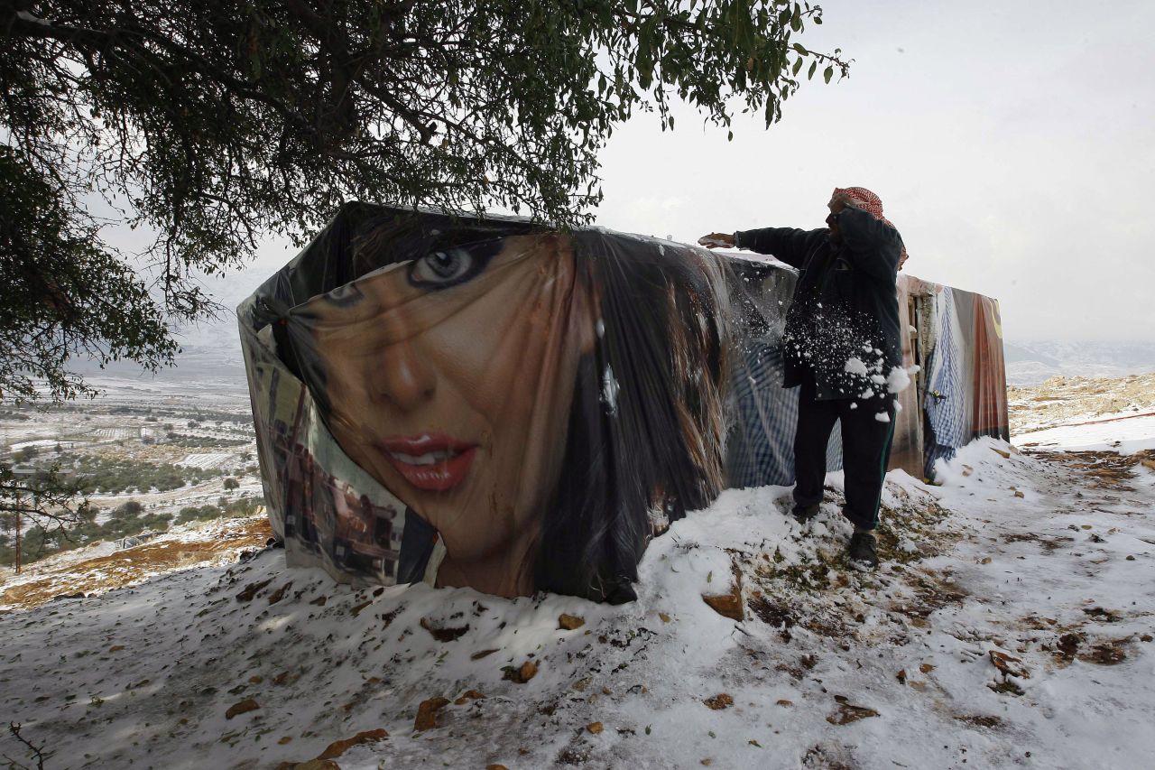 A man removes snow from the roof of his tent at a camp in Lebanon's Bekaa Valley.