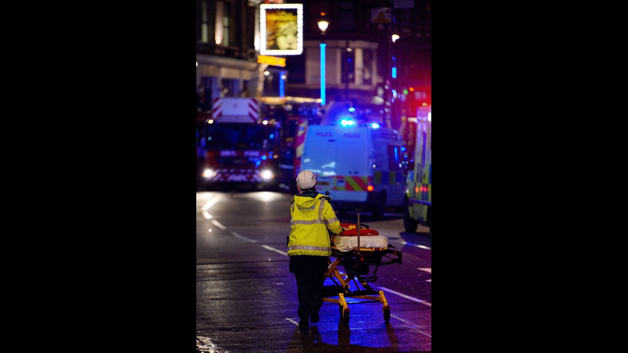 An emergency worker pushes a stretcher along Shaftesbury Avenue.
