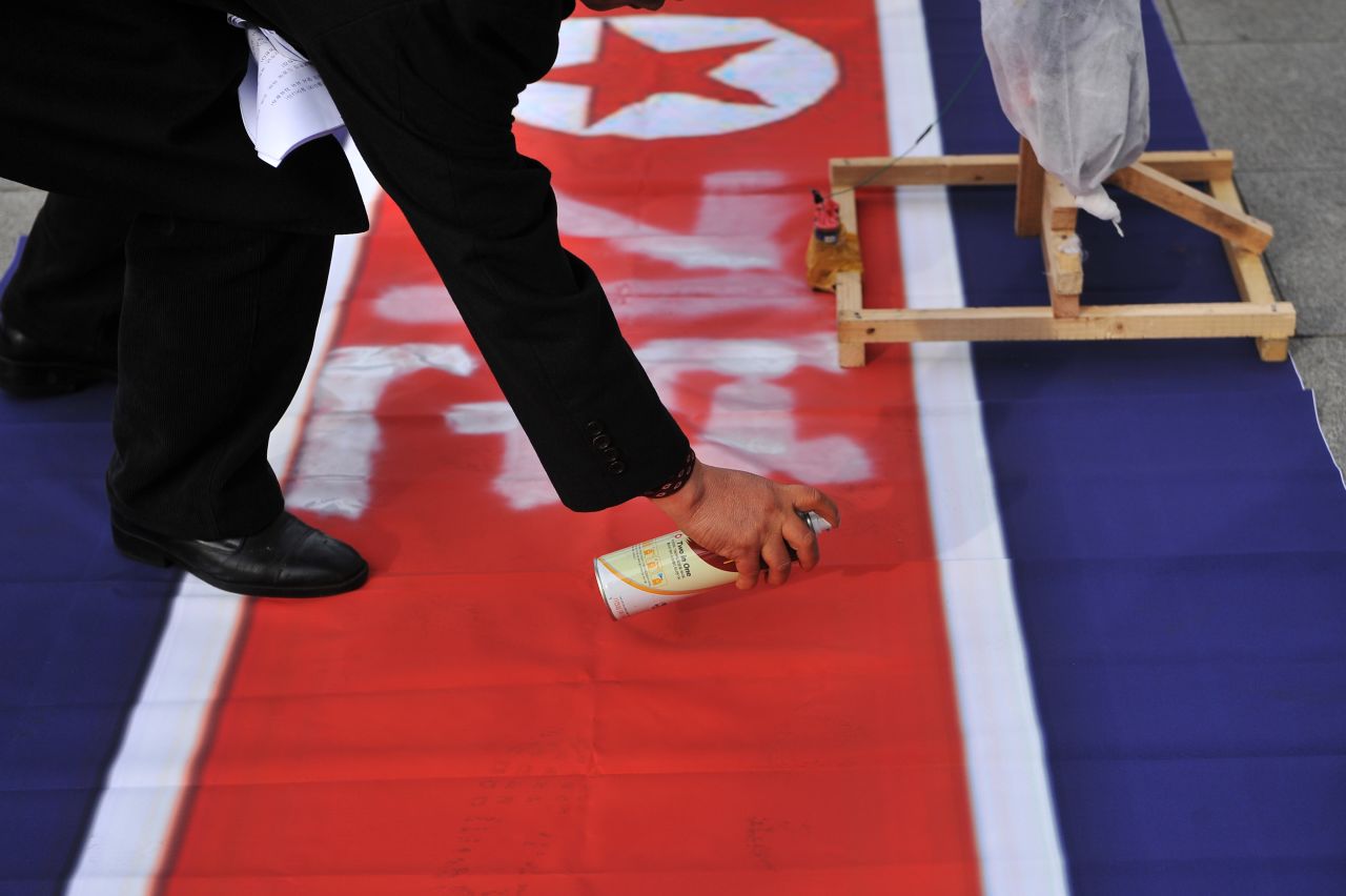 An activist sprays Korean characters that say "feeling good" on a North Korean flag before the effigies of North Korean leaders were set on fire December 17.