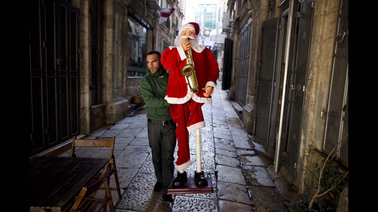 A Palestinian shop owner carries a Santa Claus figure on the street preparing for Christmas near Jaffa Gate in the Old City of Jerusalem, Israel, on December 19.