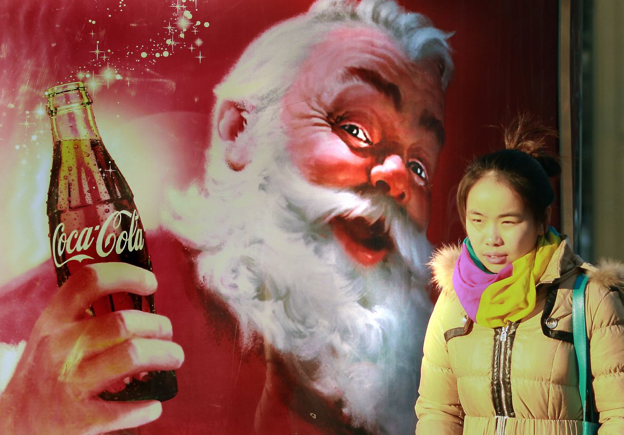 A girl walks by a Coca-Cola Christmas ad in Beijing on December 19.