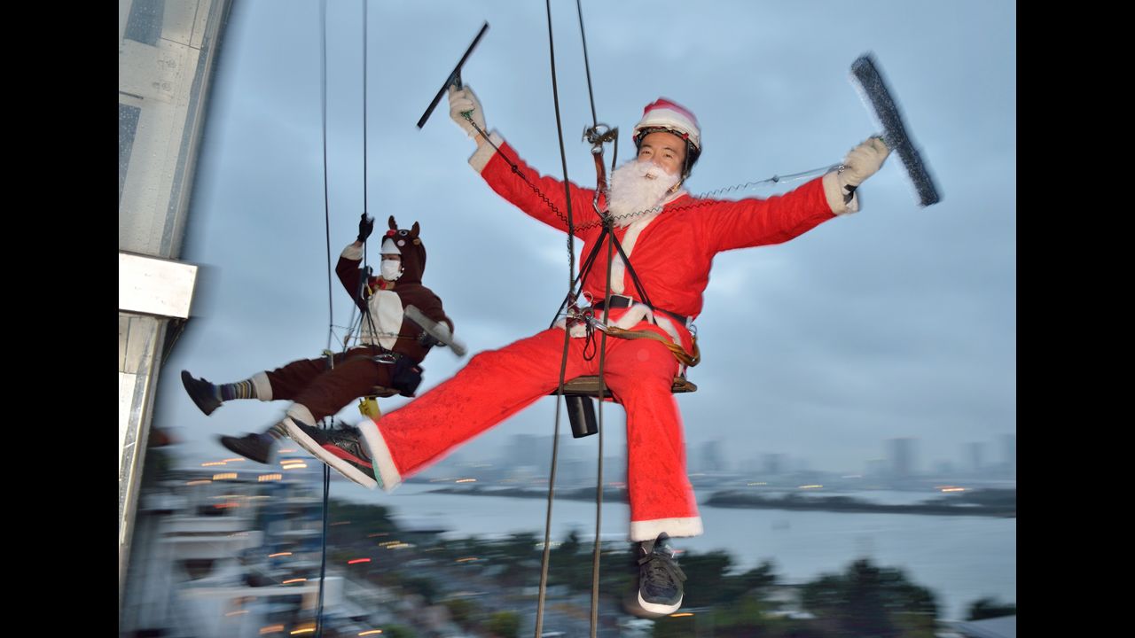 Workers wearing Santa Claus and reindeer costumes clean windows outside of a 100-foot-tall shopping mall at promotional event in Tokyo on December 19.