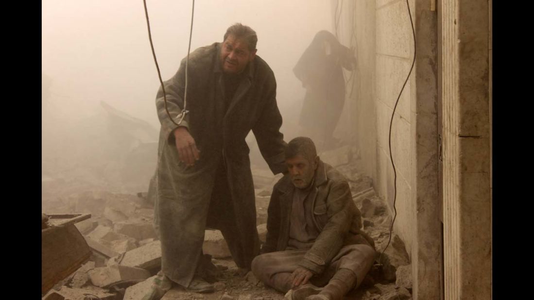 <strong>December 17: </strong>A Syrian man helps an injured man following an airstrike in Aleppo's Maadi neighborhood. Two children were among at least 13 people killed in new air strikes on a rebel-held district of Syria's main northern city of Aleppo, the Syrian Observatory for Human Rights said.