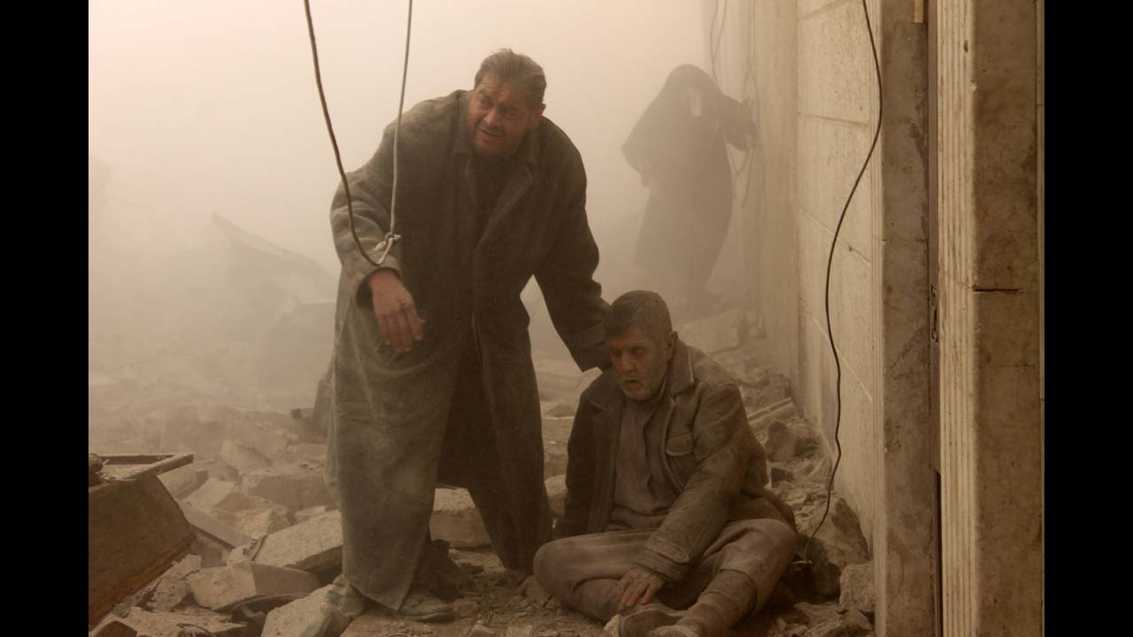 <strong>December 17: </strong>A Syrian man helps an injured man following an airstrike in Aleppo's Maadi neighborhood. Two children were among at least 13 people killed in new air strikes on a rebel-held district of Syria's main northern city of Aleppo, the Syrian Observatory for Human Rights said.