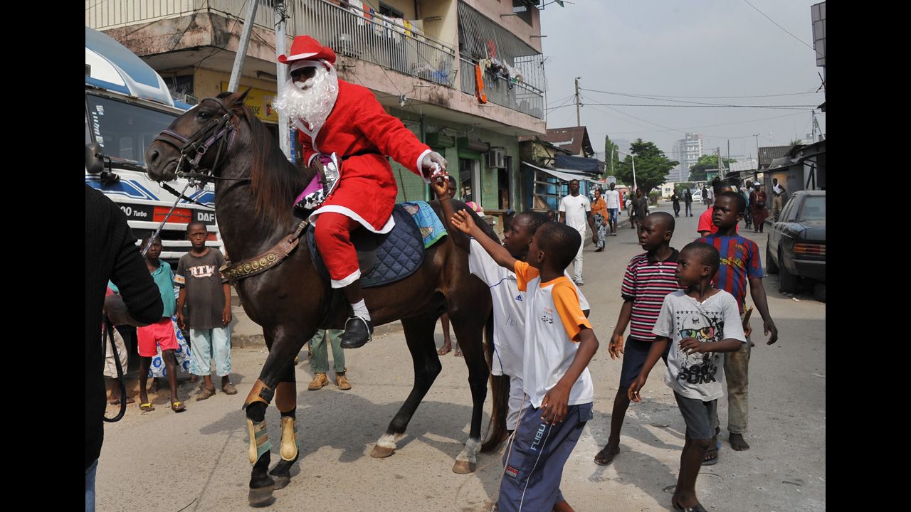 A man wearing a Santa Claus costume rides a horse and distributes gifts to children in a street of Abidjan, Ivory Coast, on December 20.