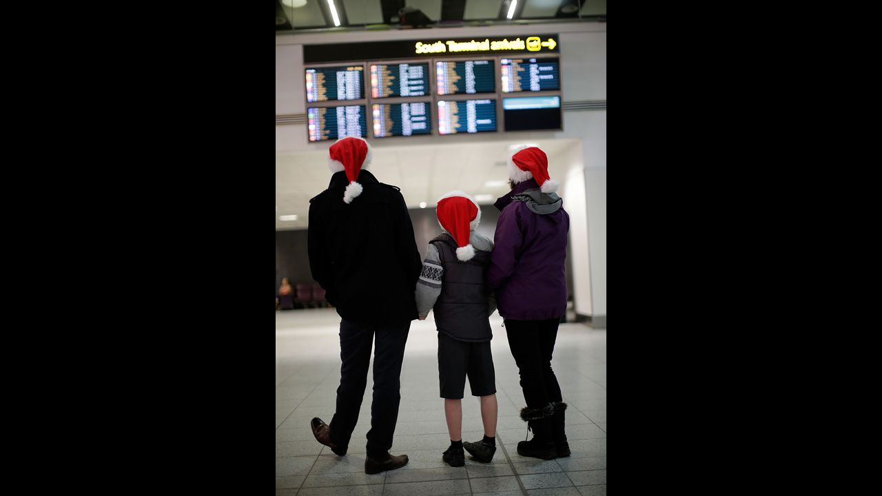 Andy, Harvey and Dianne Thorn look at the arrivals board at Gatwick airport on December 20 in London. Large numbers of people are using the transport system to return home or head off on holiday. 