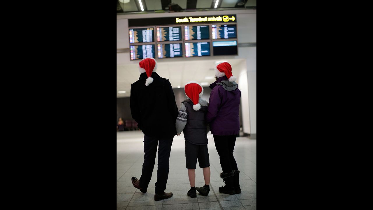 Andy, Harvey and Dianne Thorn look at the arrivals board at Gatwick airport on December 20 in London. Large numbers of people are using the transport system to return home or head off on holiday.