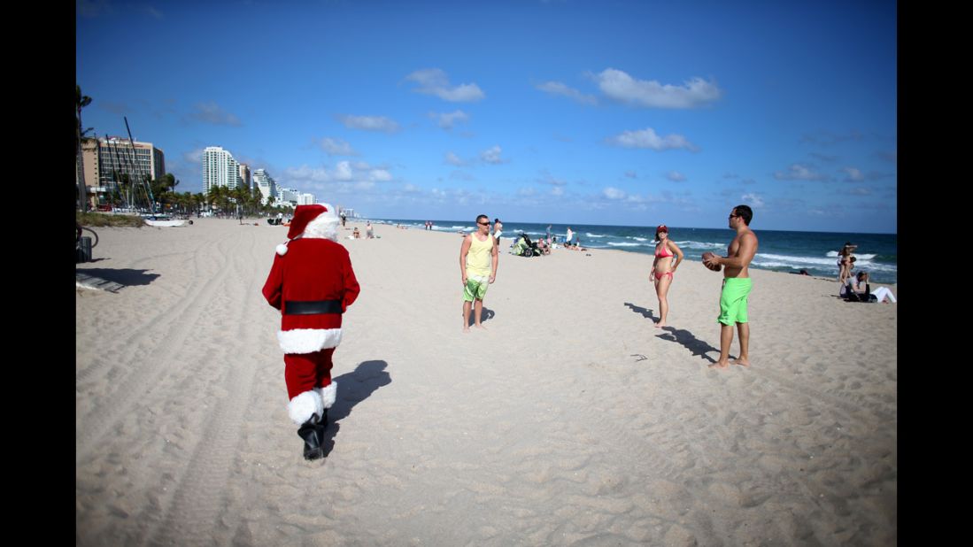 Tom Tapp dressed as Santa Claus walks along the beach passing out candy canes and posing for pictures with beachgoers on December 20, in Fort Lauderdale, Florida.