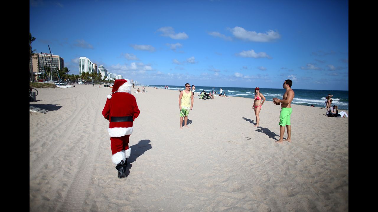Tom Tapp dressed as Santa Claus walks along the beach passing out candy canes and posing for pictures with beachgoers on December 20, in Fort Lauderdale, Florida.