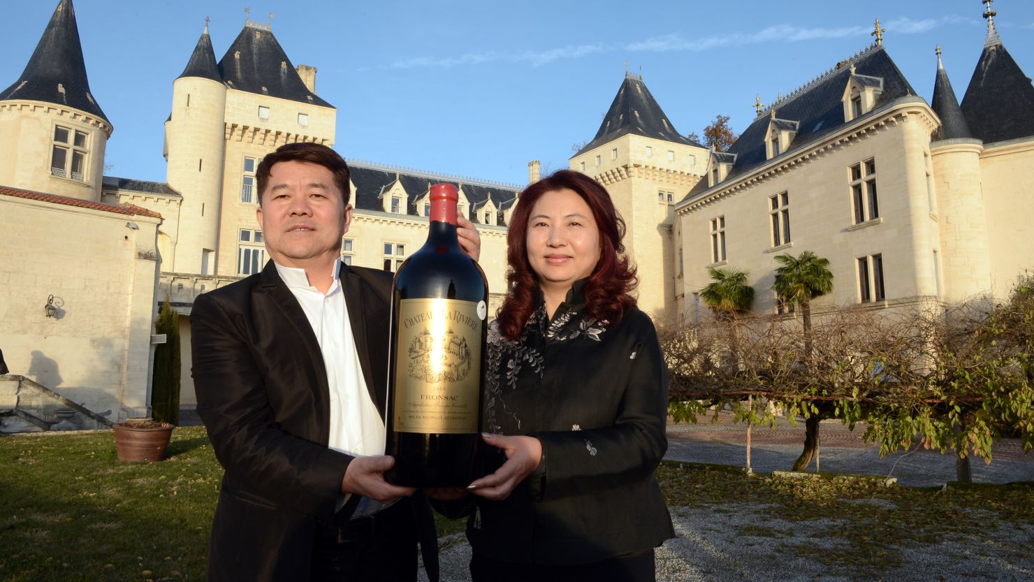 Lam Kok and his wife pose for a photograph Friday in front of the Chateau de La Riviere, in La Riviere. 