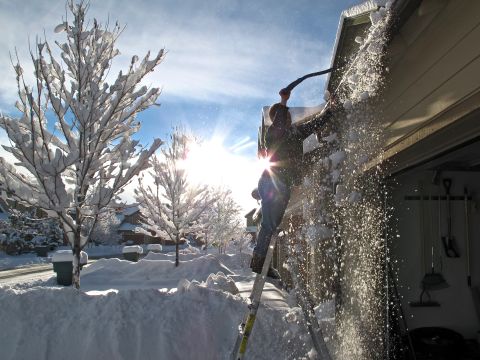 Keola Wong removes snow from the roof of his Bellemont, Arizona, home on Friday, December 20. A storm system dropped heavy snow in northern Arizona, while Phoenix-area streets and highways were wet from rain during the morning commute. 