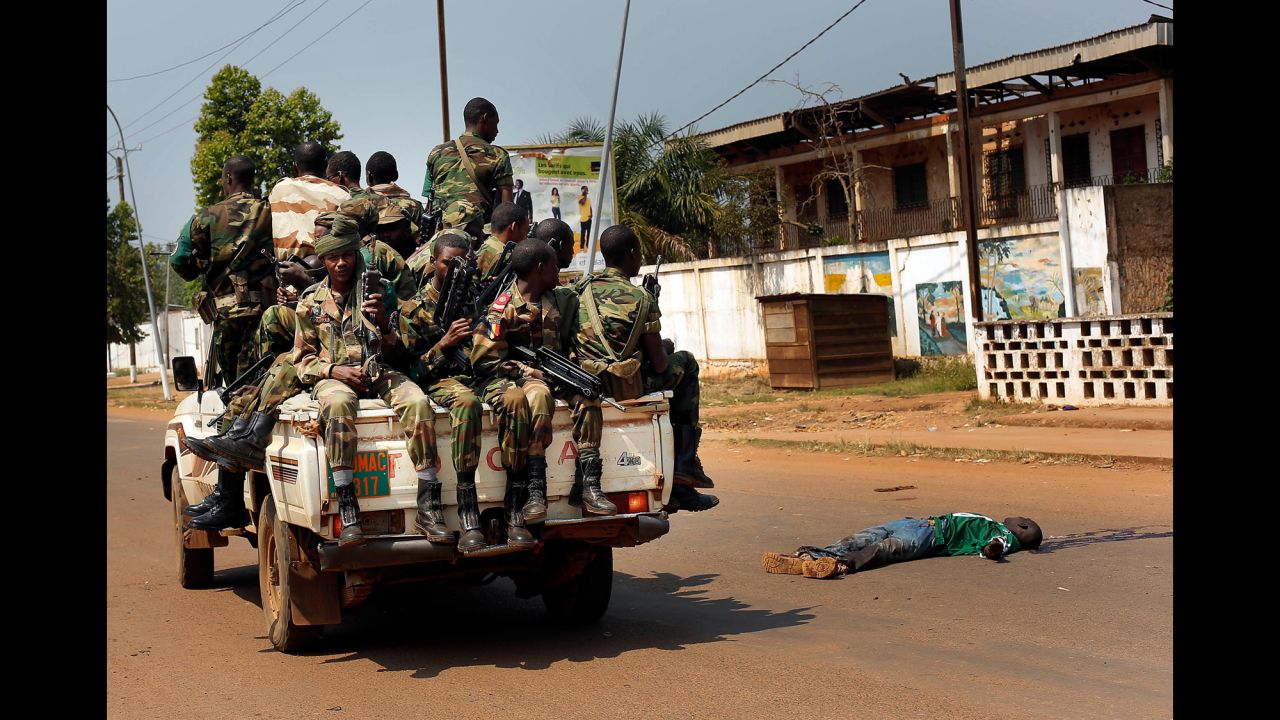 <strong>December 20:</strong> Chadian troops from a multinational African peacekeeping force drive past the body of a man who was suspected of having been an ex-Seleka militiaman, in Bangui, the capital of the violence-wracked Central African Republic.