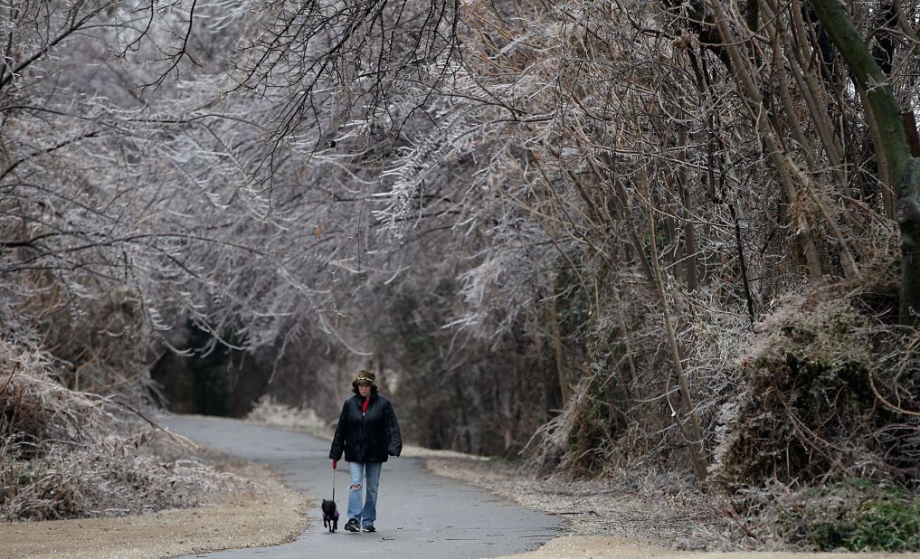Debra Guthrie walks her dog along a trail surrounded by ice-covered trees in Tulsa, Oklahoma, on December 21. 