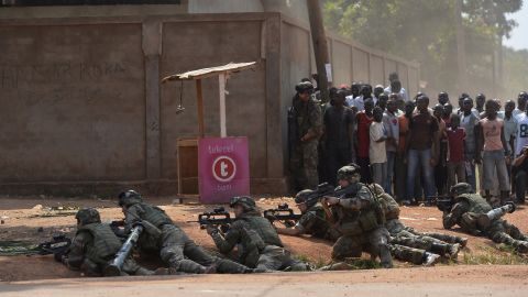 People watch as French soldiers hold their position on a street in Bangui after hearing gunshots on December 20.