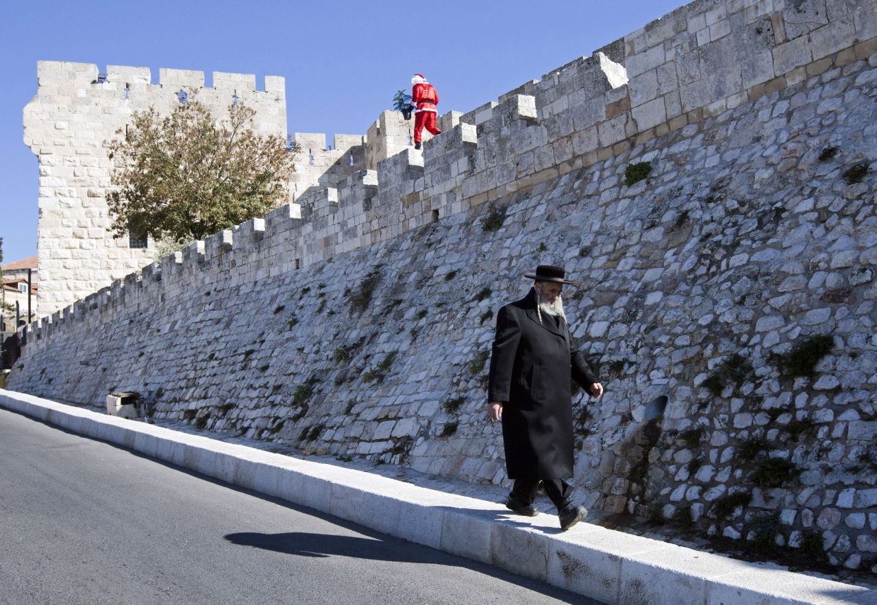 An ultra-Orthodox Jew walks beneath a Palestinian man dressed up as Santa Claus along the walls of Jerusalem's Old City on Sunday, December 22.