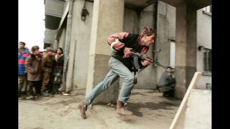An anti-Communist civilian fighter runs with an AK-47 during a street-fight in Bucharest, Romania, in 1989.