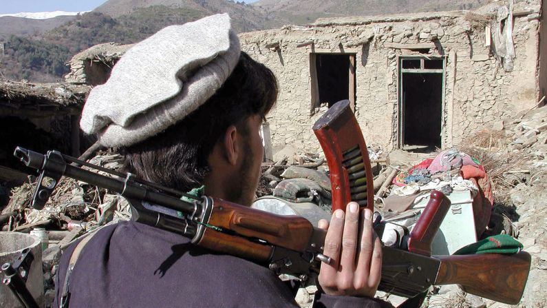 A Pakistani tribesman carries an AK-47 assault rifle after an air strike in Damadola, Pakistan, in 2006.